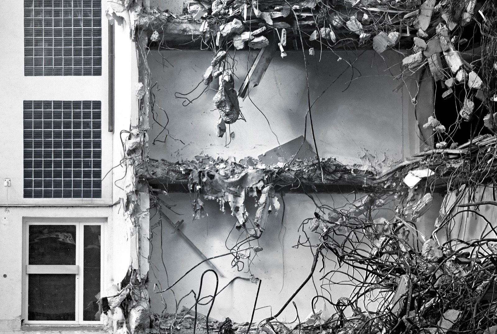Black and white photograph of a demolition site: torn open
                  floor slabs, reinforcement bars hanging out