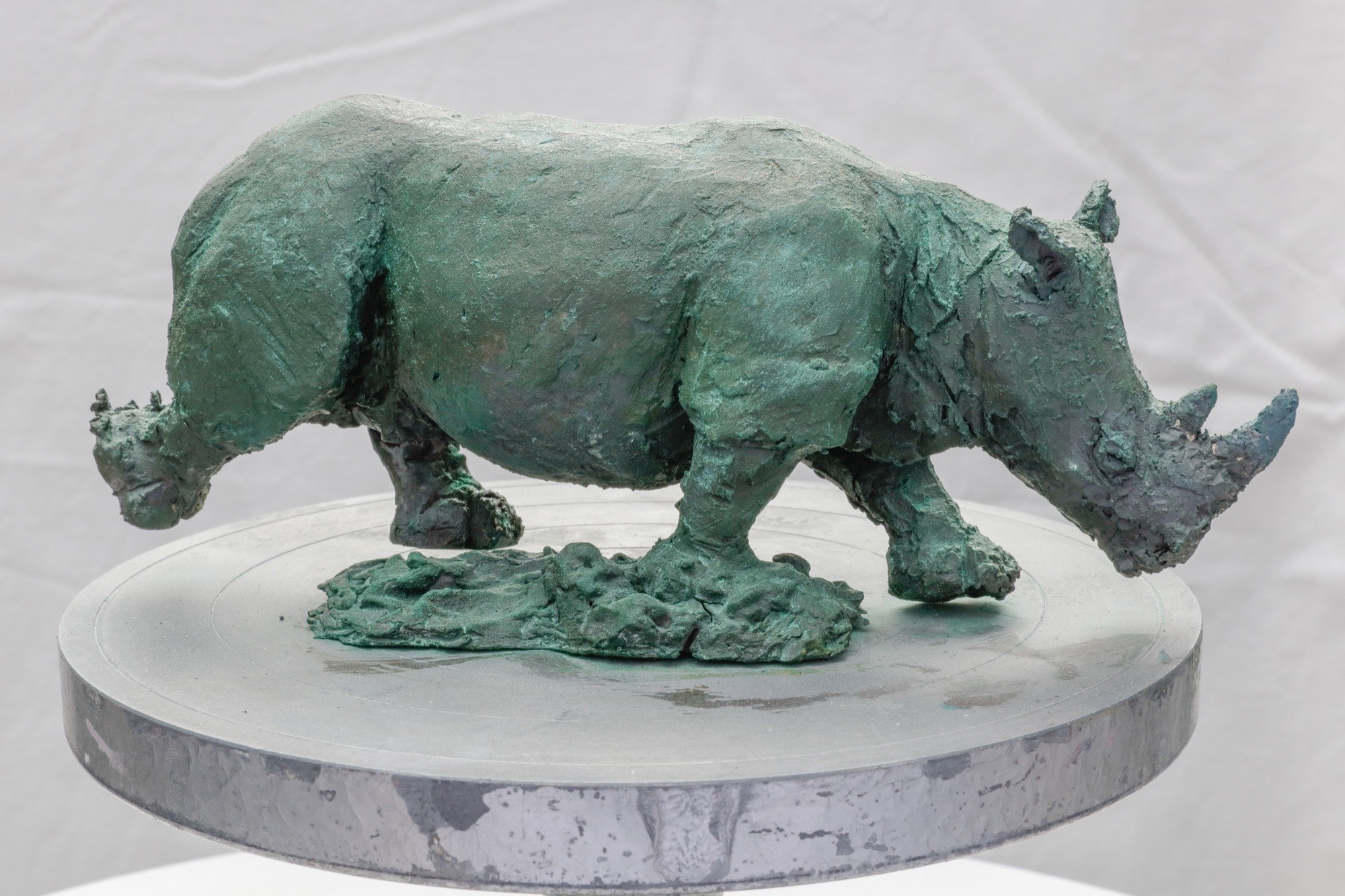 Clay sculpture of a rhinoceros on a round base